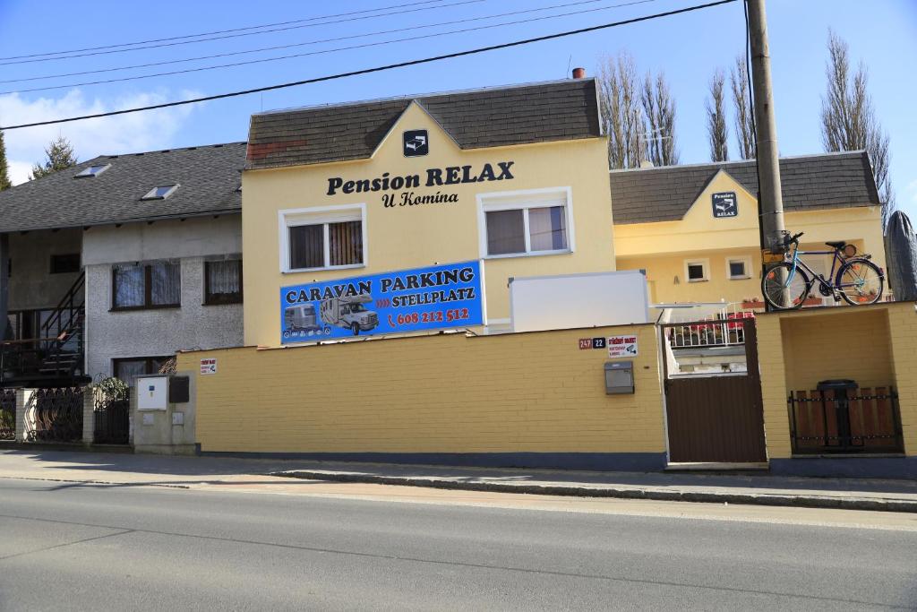 弗兰季谢克矿泉镇Pension RELAX U Komína的黄色的建筑,旁边标有标志