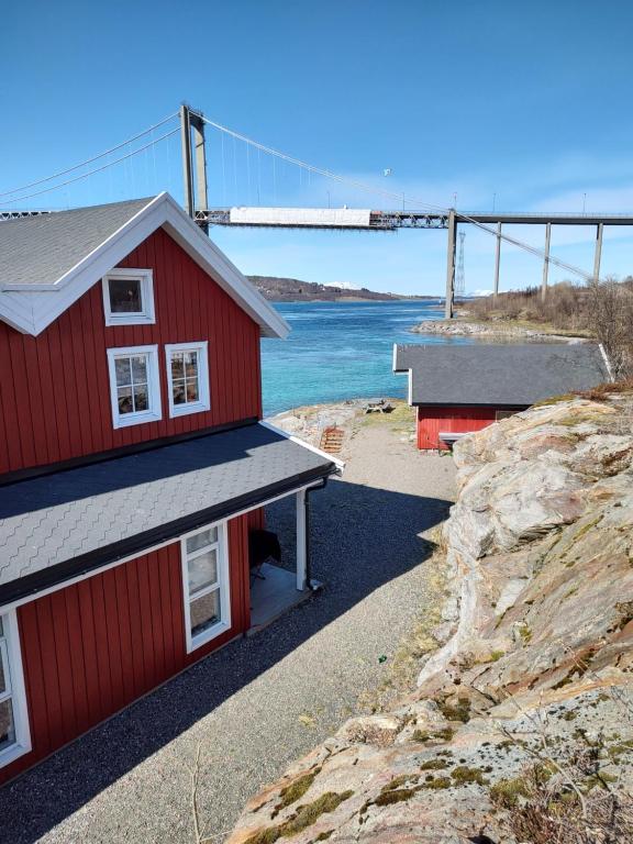 伊温斯科尔Tjeldsundbrua Overnatting - Sjøhus1的山丘上两座红色的建筑,后方有一座桥