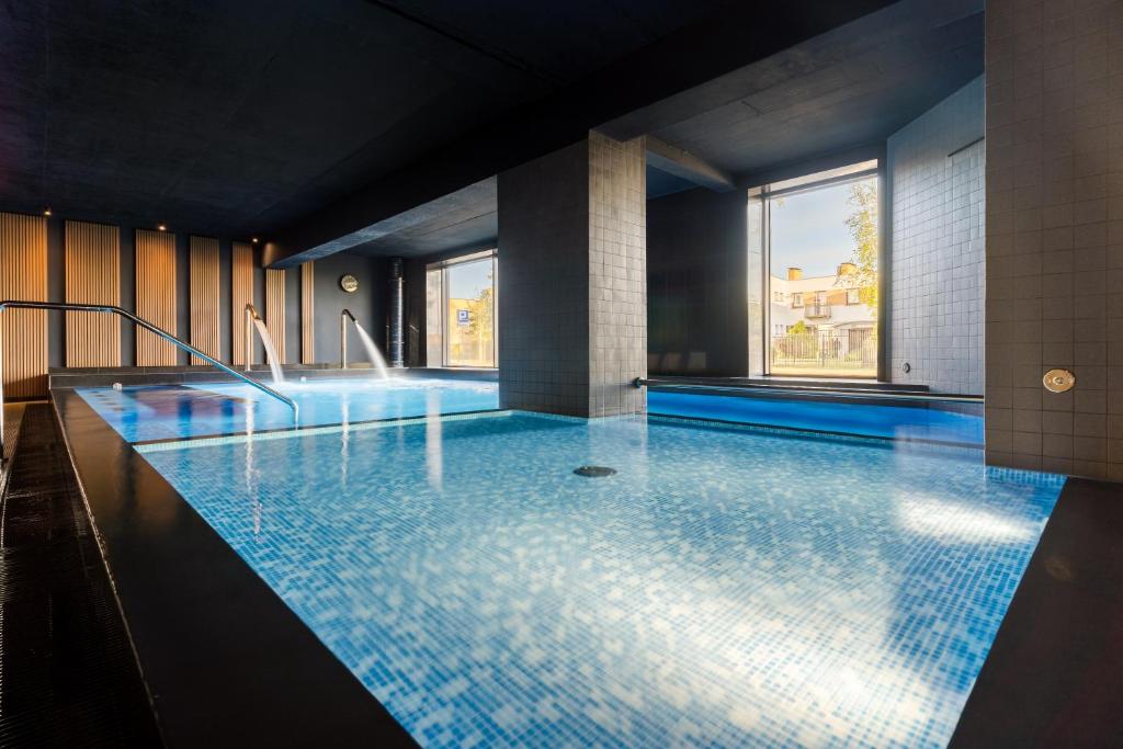 韦巴威尔第游乐水疗别墅酒店的大楼内一个蓝色瓷砖的大型游泳池