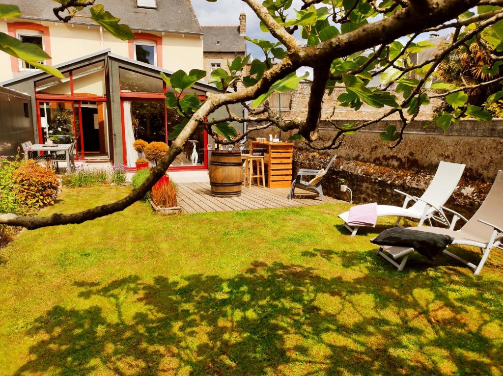 圣布里厄Aux Trois Palmiers的一个带躺椅和房屋的庭院