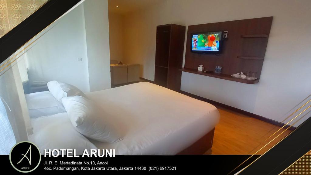 雅加达Hotel Aruni Ancol的一间酒店客房,配有一张床和一台电视