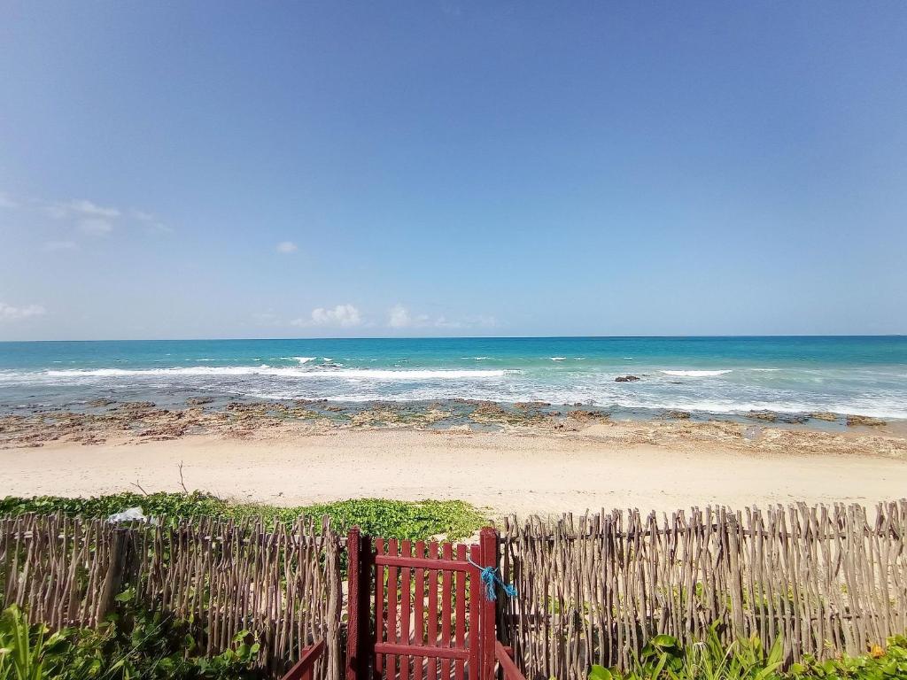 泰巴Casa dos Ximenes - Beira Mar da Taíba - Ótima localização的海滩上的木栅栏与海洋