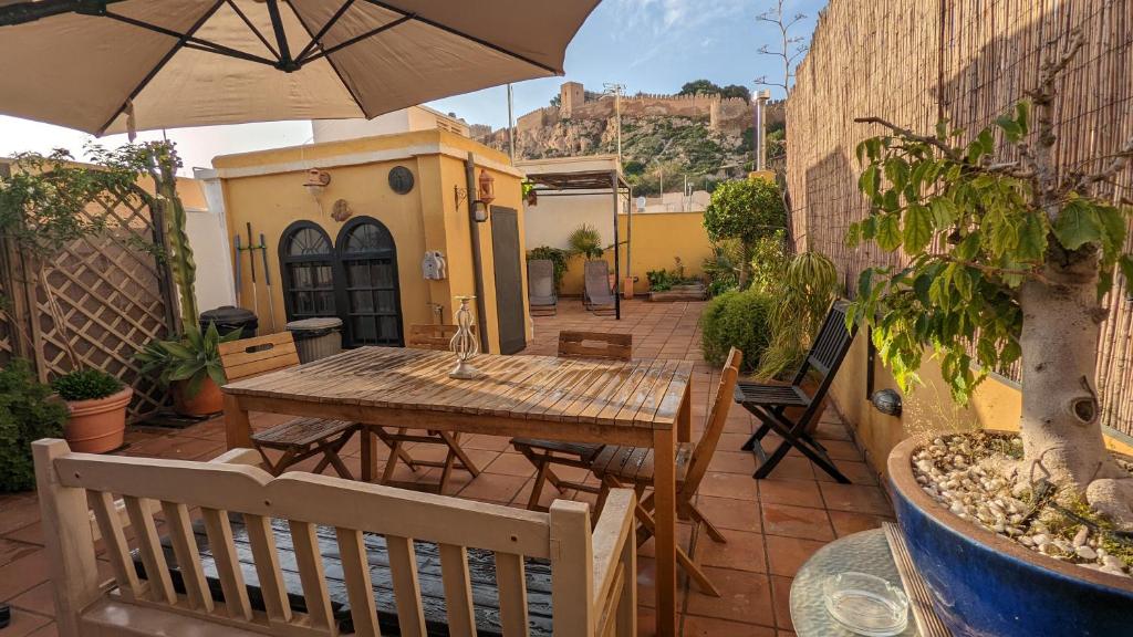 阿尔么丽亚La Casa Azul Almería的庭院配有木桌和遮阳伞。