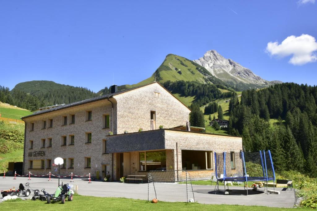 沃瑟姆阿尔伯格Am Gehren - Arlberg Appartements的一座大石头建筑,背景是一座山