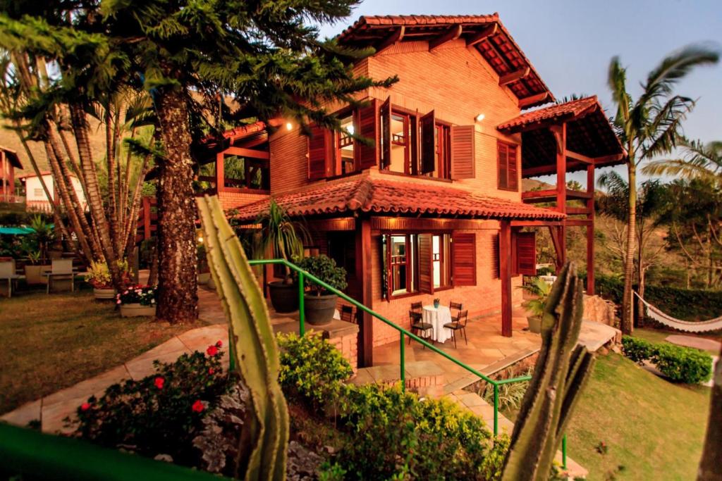 布鲁马迪纽Temporada Retiro do Chalé Brumadinho MG的前面有棕榈树的房子