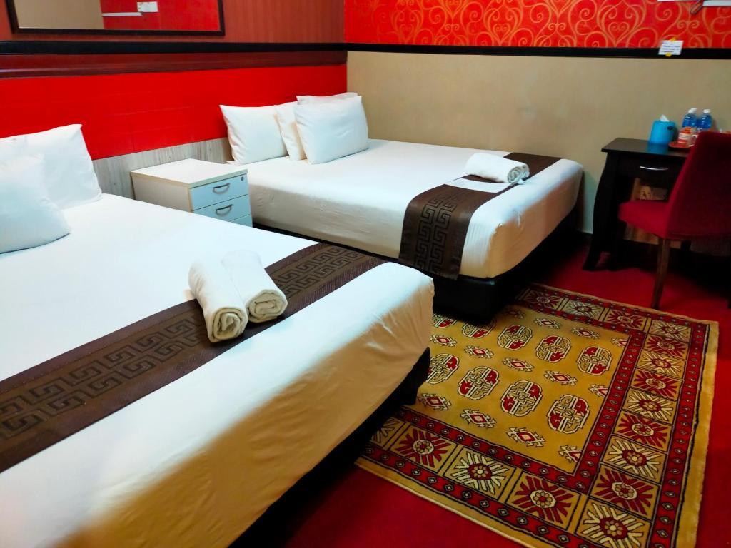 新山HOTEL SRI IMPIAN的酒店客房设有两张床和红色的墙壁。