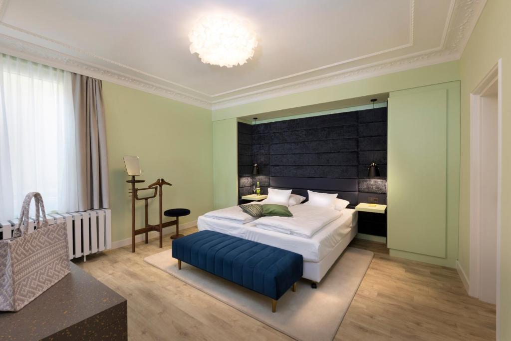 蒂宾根Hotel Krone ****S的一间卧室配有一张大床和蓝色的搁脚凳