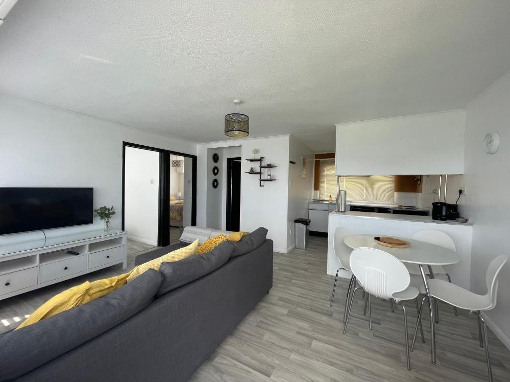 新罗姆尼Romney Sands Holiday Apartment的带沙发和桌子的客厅以及厨房。