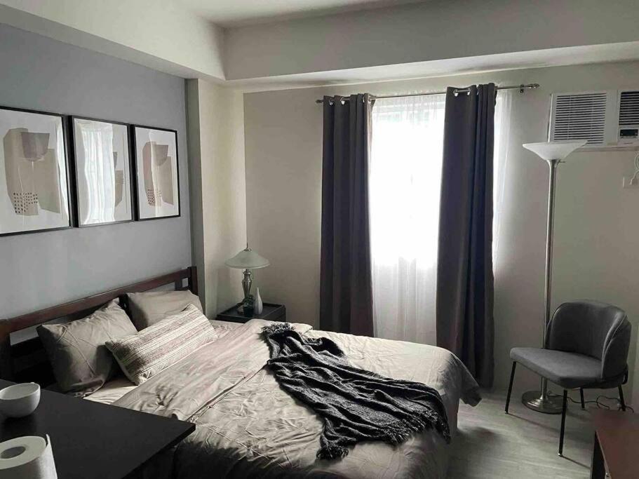 曼达维市Cozy Condominium near Mactan International Airport的卧室配有床、椅子和窗户。