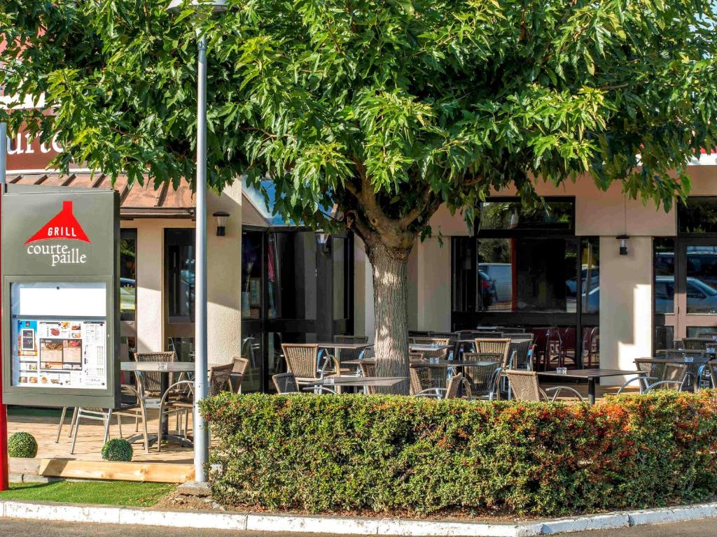 布拉尼亚克ibis Toulouse Aeroport的室外咖啡厅配有桌椅和一棵树