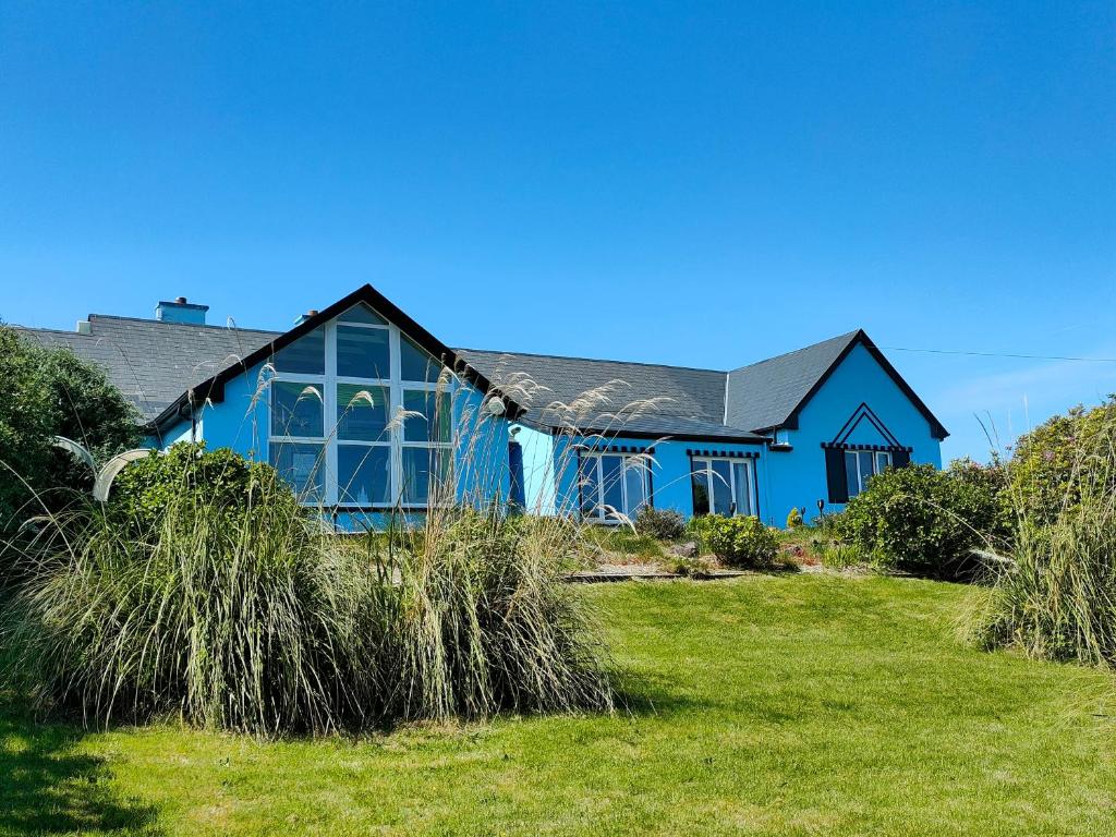 基尔芬代尔豪华精品住宿加早餐旅馆的前面有高大的草的蓝色房子