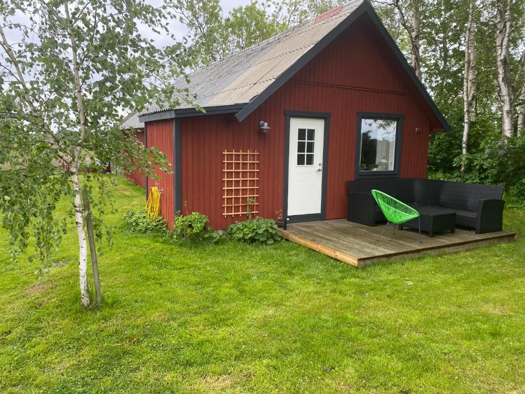 奥胡斯Lilla Sandslätt的红色的棚子,配有甲板和绿色的椅子