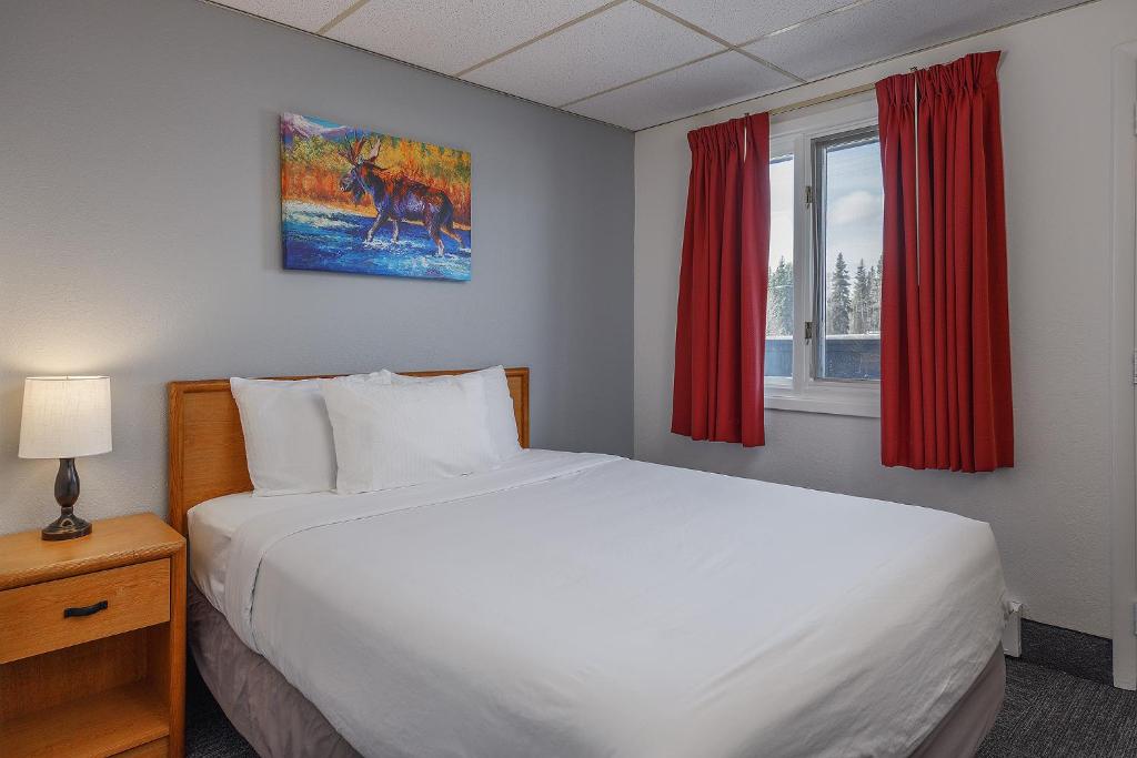费尔班克斯Golden North Inn的卧室配有一张带红色窗帘的大型白色床