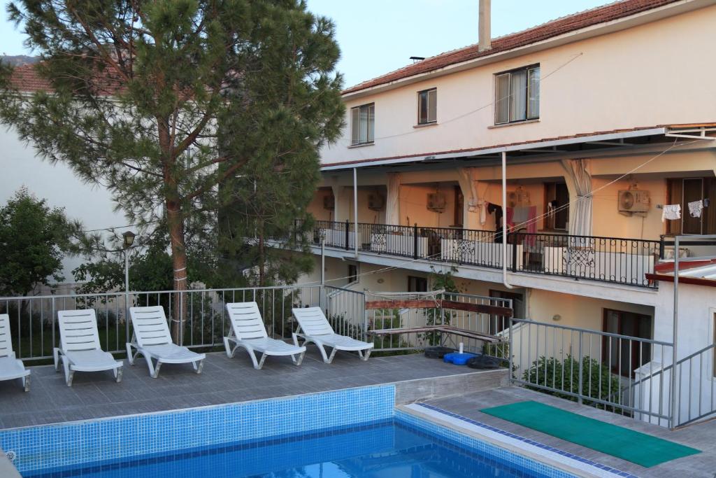 帕莫卡莱GÜNEŞ APART OTEL的一座建筑旁的带游泳池和椅子的酒店