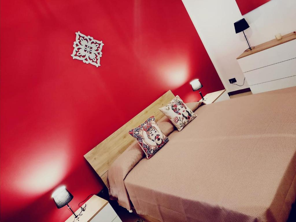 奇尼斯La Sicilia in casa的红色卧室配有带枕头的床