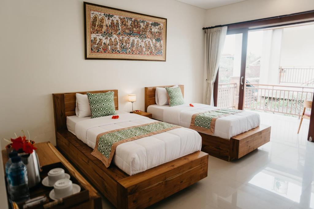 乌布Tu Sandat Homestay的一间带两张床的卧室和一个阳台
