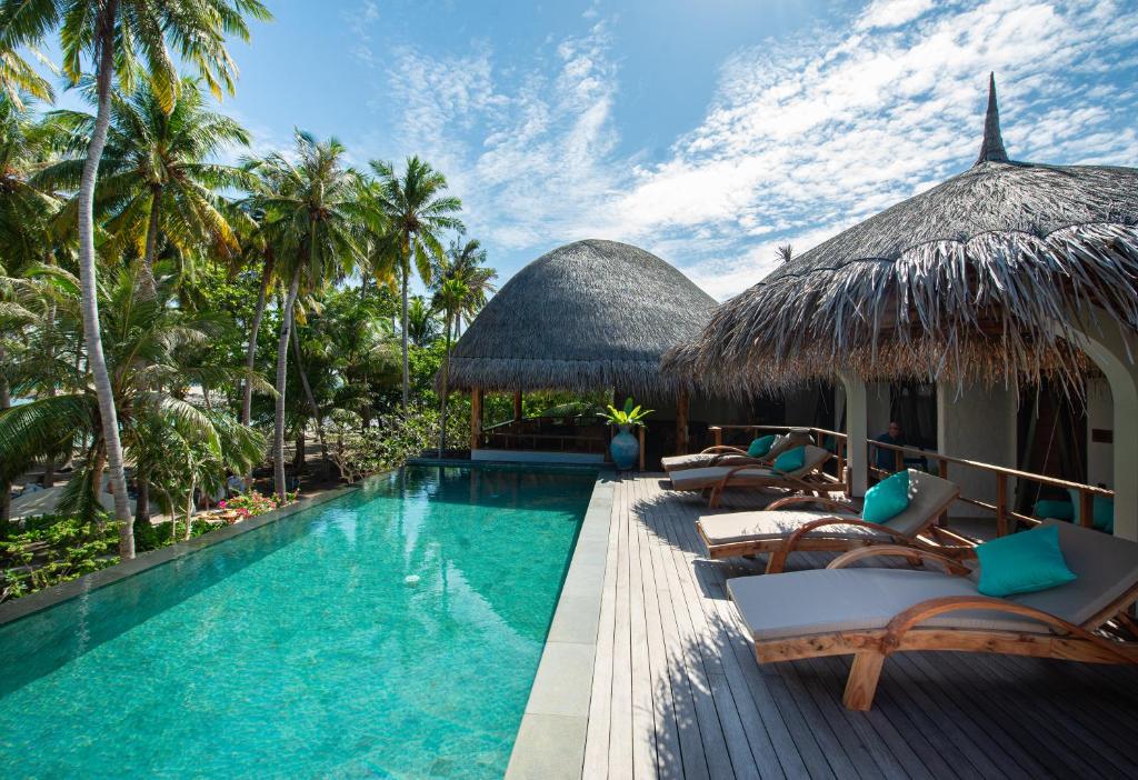 福拉杜岛Island Luxury Boutique Hotel - Fulhadhoo的毗邻度假酒店的带椅子和遮阳伞的游泳池