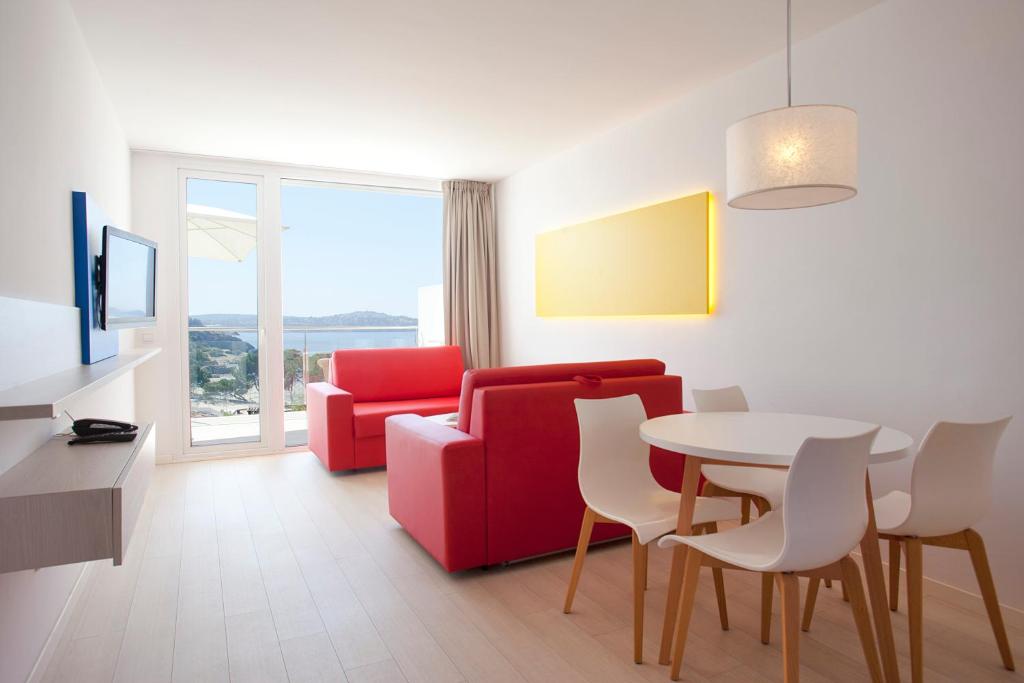 帕格拉新海洋公寓式酒店的客厅配有红色的沙发和桌子