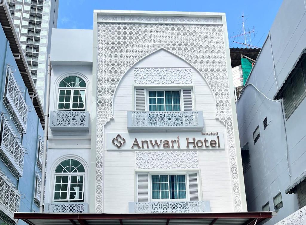 曼谷Anwari Hotel的一座白色的建筑,上面有箭牌酒店标志