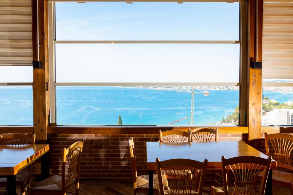 伏罗拉Aerial Hotel & Spa的餐厅设有桌椅和大窗户。