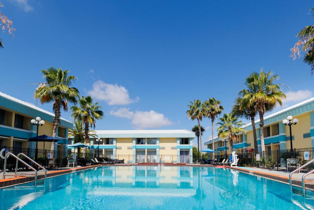 奥兰多Garnet Inn & Suites, Orlando的棕榈树酒店前的大型游泳池