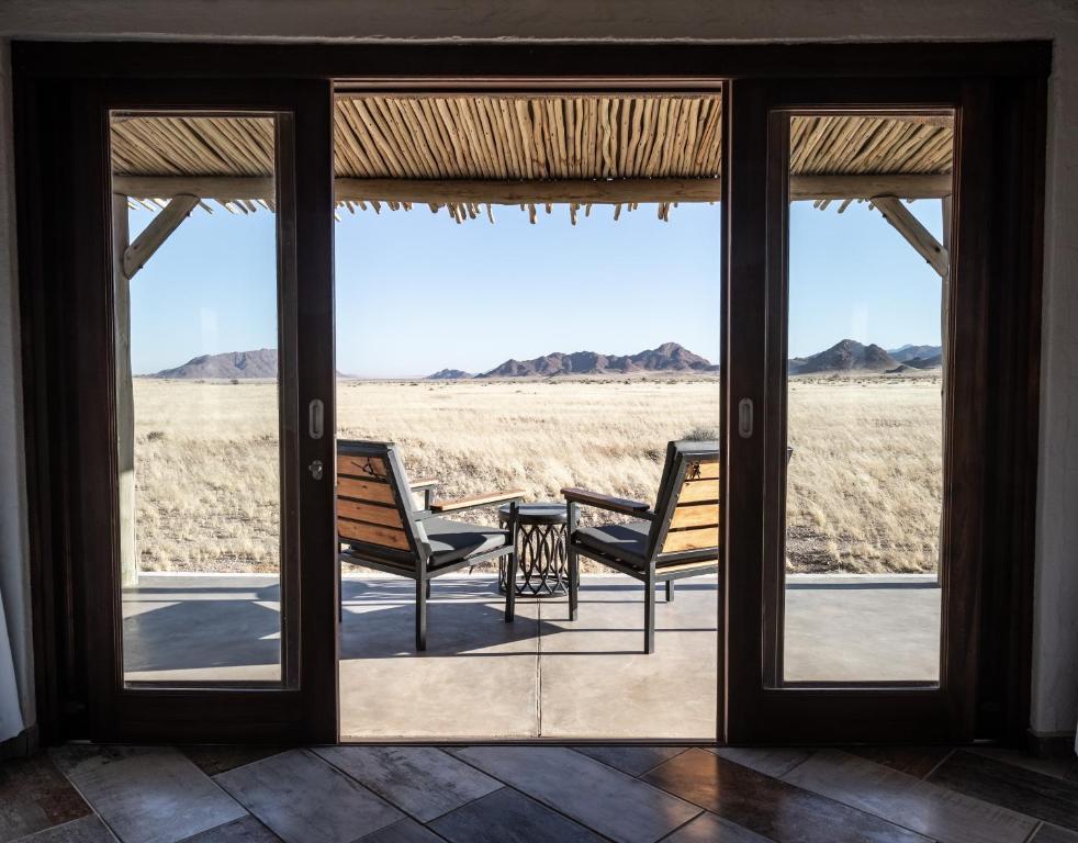 塞斯瑞姆Desert Homestead Lodge的一个带两把椅子的门廊,享有沙漠的景色