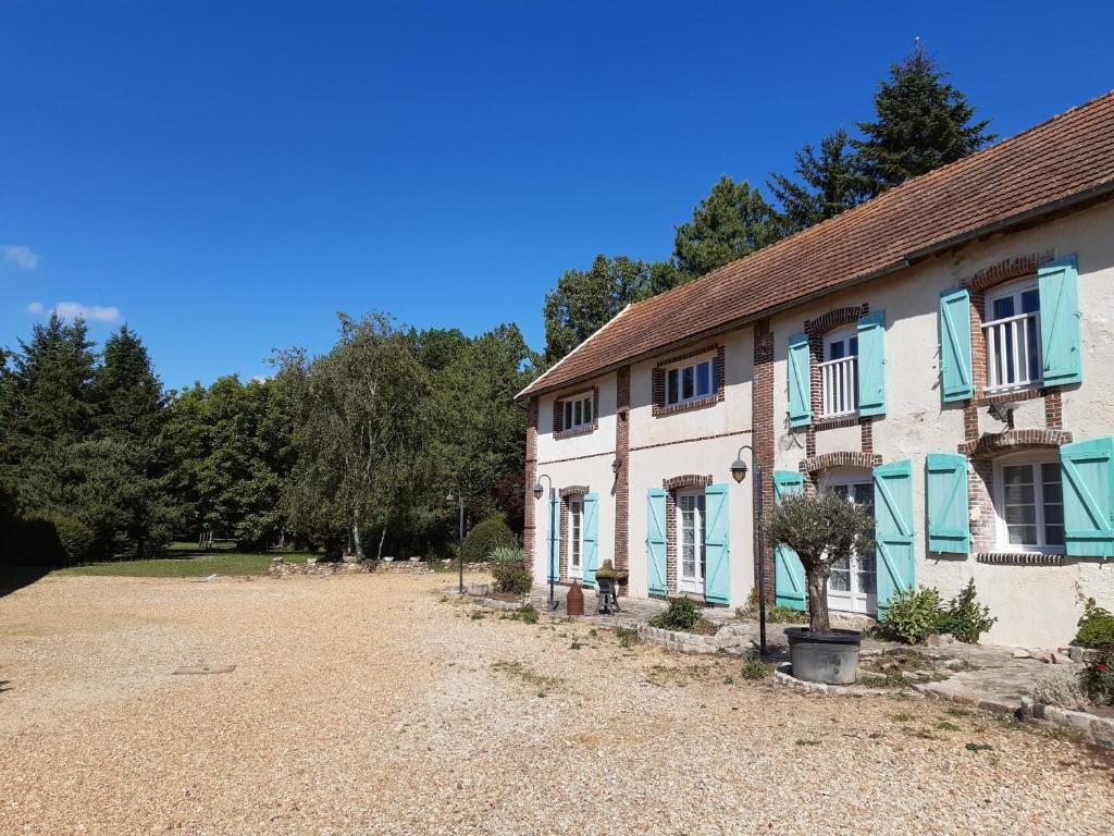 Villiers-le-MorhierAu Charme de l'Eure的蓝色窗户和碎石车道的房子