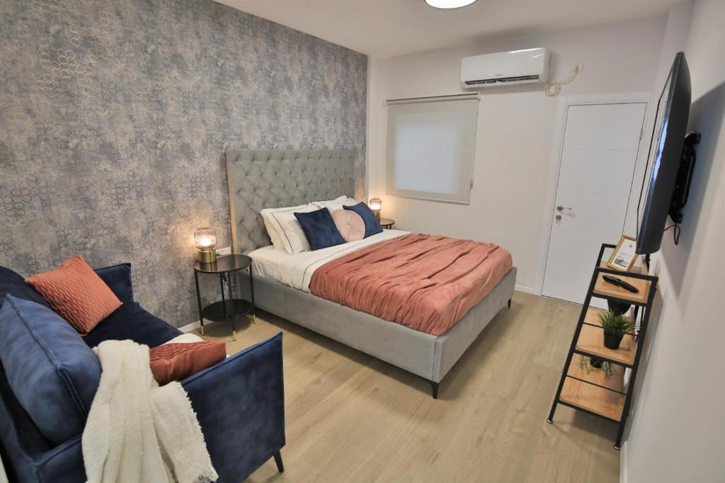 内坦亚Cozy and stylish 1-bedroom apartment的一间卧室配有一张床、一张沙发和一台电视。