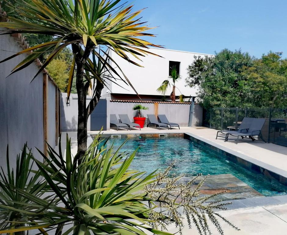 佩罗勒Appartement Pérols Centre的一个带椅子的游泳池,并种植了棕榈树