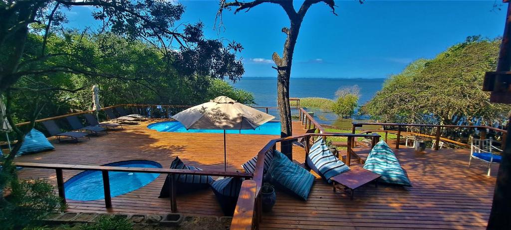 赫卢赫卢韦Nibela Lake Lodge by Dream Resorts的木制甲板配有蓝色枕头和雨伞
