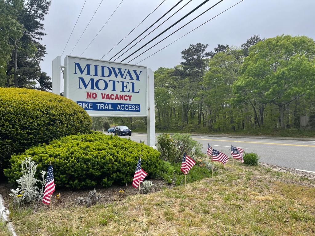 伊斯特姆Midway Motel & Cottages的路旁挂有美国国旗的汽车旅馆标志