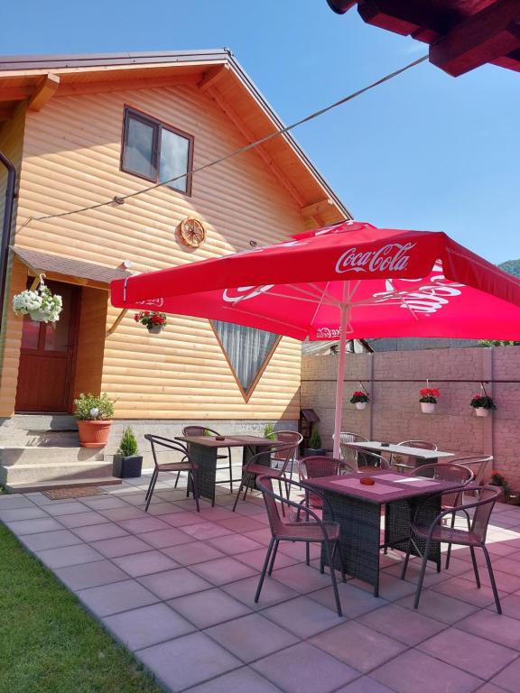 泽尔内什蒂Cabana Rustica Georgeta的一个带桌椅和红色遮阳伞的庭院