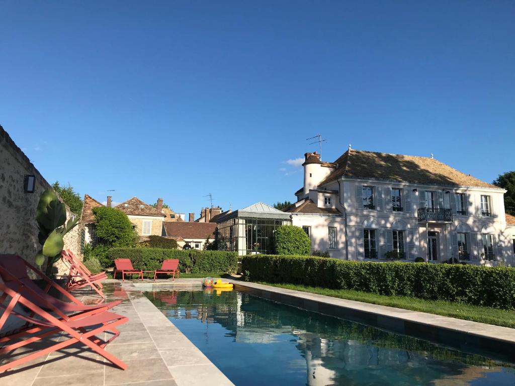 Neauphle-le-Château克洛斯圣尼古拉斯酒店的大楼前带游泳池的房子