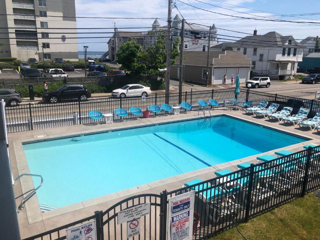 旧奥查德比奇Executive Motel的一个带椅子的大型蓝色游泳池和停车场