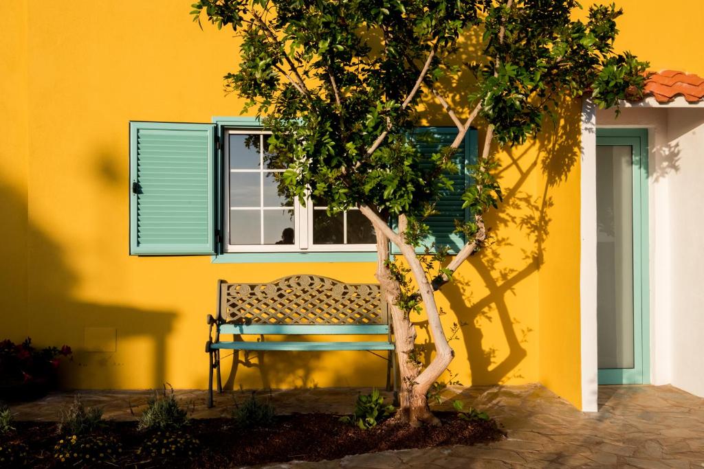 阿德耶La Finquita - Adeje的黄色建筑前面的长凳,有树