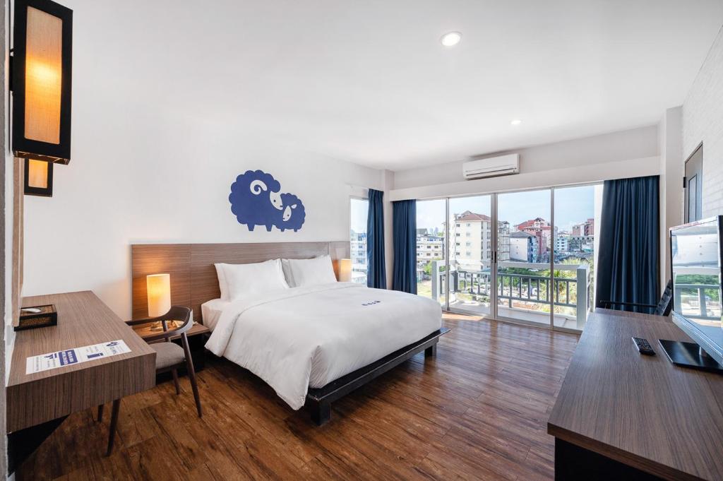 芭堤雅市中心Kokotel Pattaya South Beach的一间卧室设有一张床和一个享有美景的大窗户