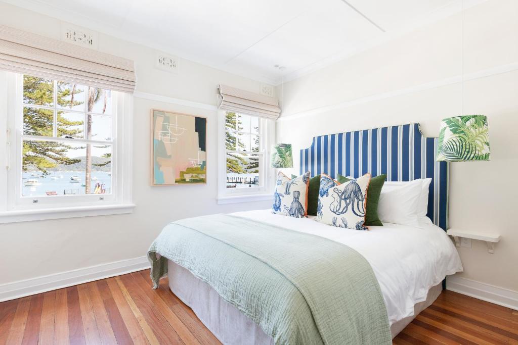 棕榈滩Barrenjoey House的白色卧室配有一张蓝色和白色条纹的大床