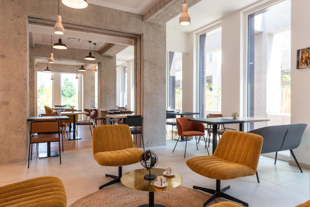 塞纳河畔伊夫里The Originals Résidence Le Monde Paris Ivry Confluence的餐厅设有桌椅和窗户。