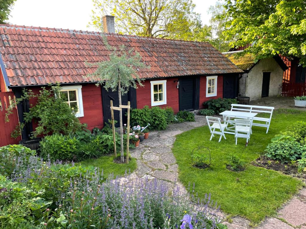 费尔耶斯塔登Ölandsgården的花园内的红色小屋,配有桌椅