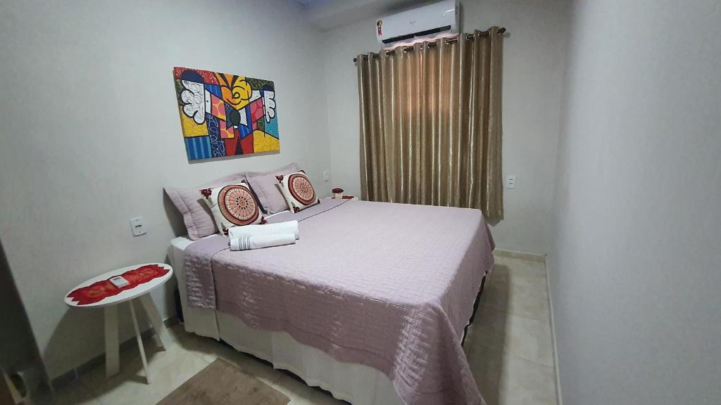 马瑙斯Hospedagem da Almira - Apartamento 2的卧室配有一张床,墙上挂有绘画作品