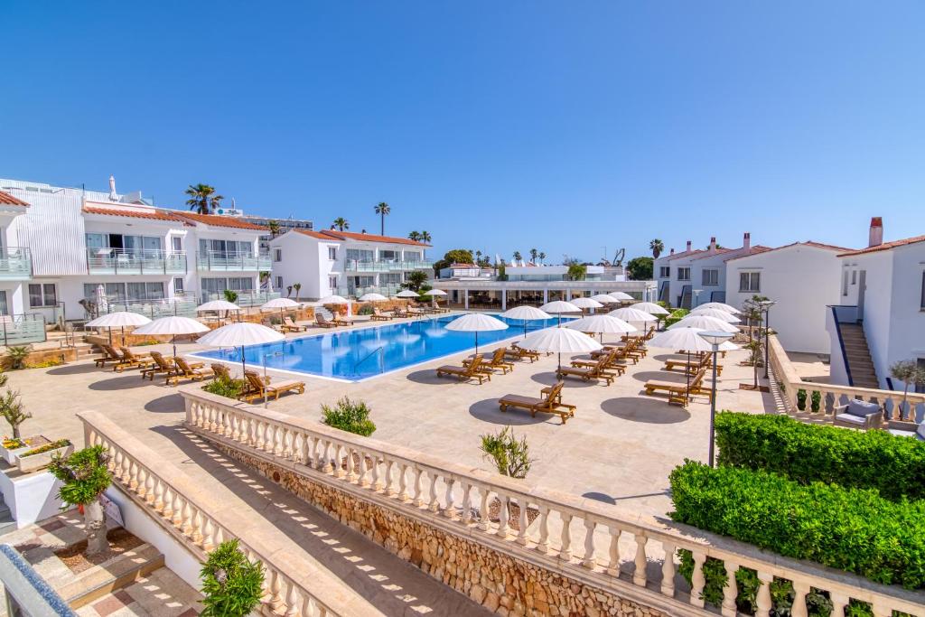萨尔加Naranjos Resort Menorca的一个带游泳池、椅子和遮阳伞的度假村