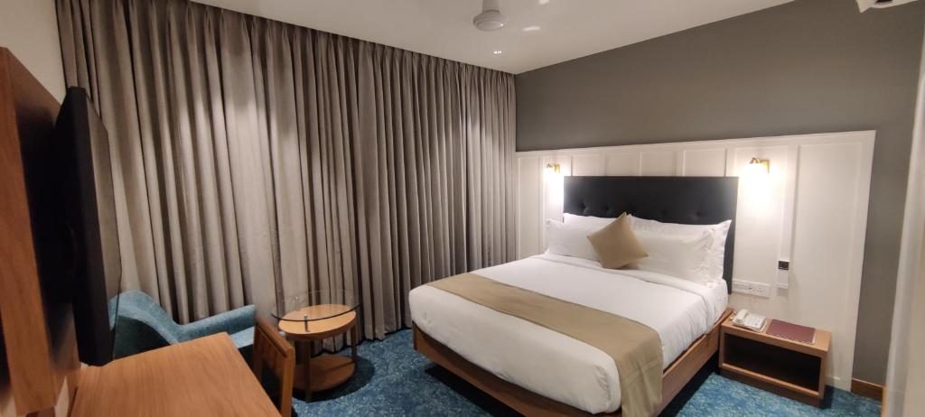 AnkleshwarChryso Hotels Pvt Ltd的酒店客房配有一张床、一张桌子和一把椅子。