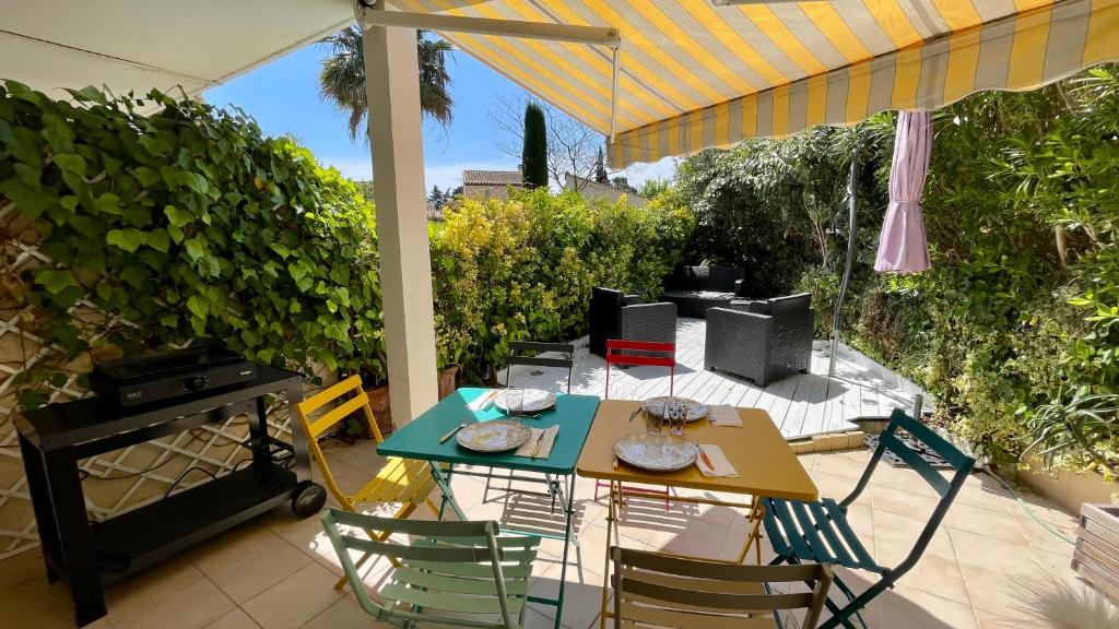 弗雷瑞斯Mon petit Paradis sur SAINT-AYGULF的露台的遮阳伞下的桌椅