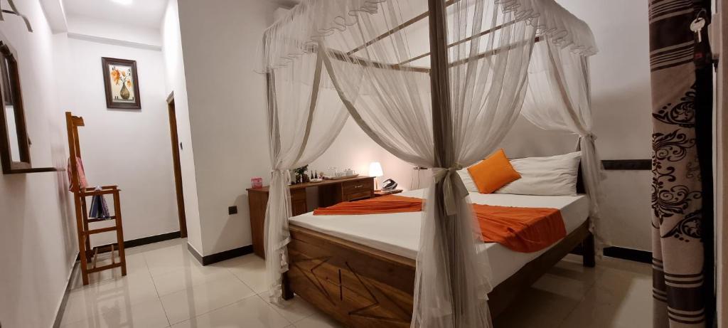 米瑞莎Maduranga n Guest的一间卧室配有带橙色枕头的天蓬床