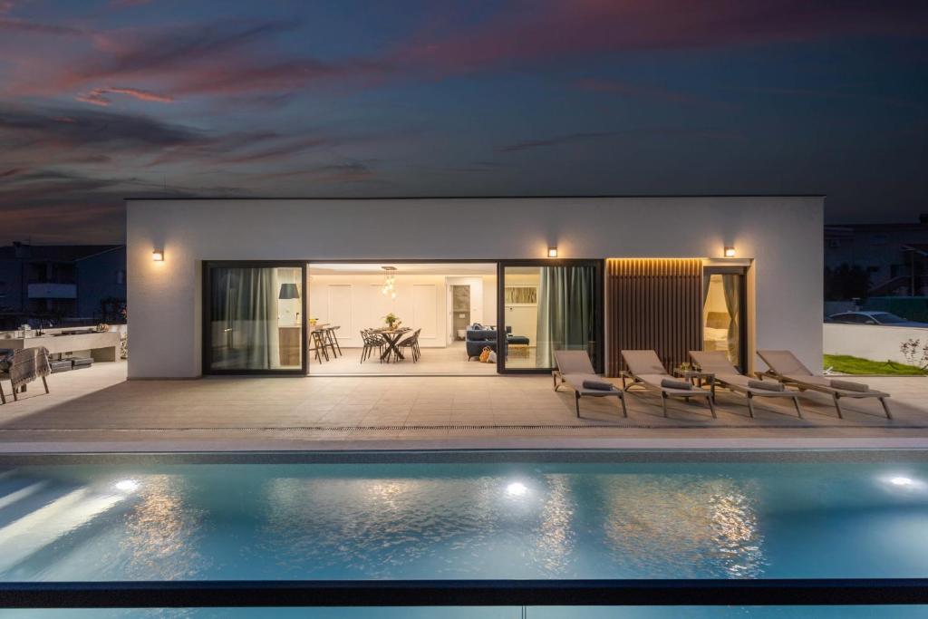 沃希Villa Coralis With Heated Pool的夜间带游泳池的别墅