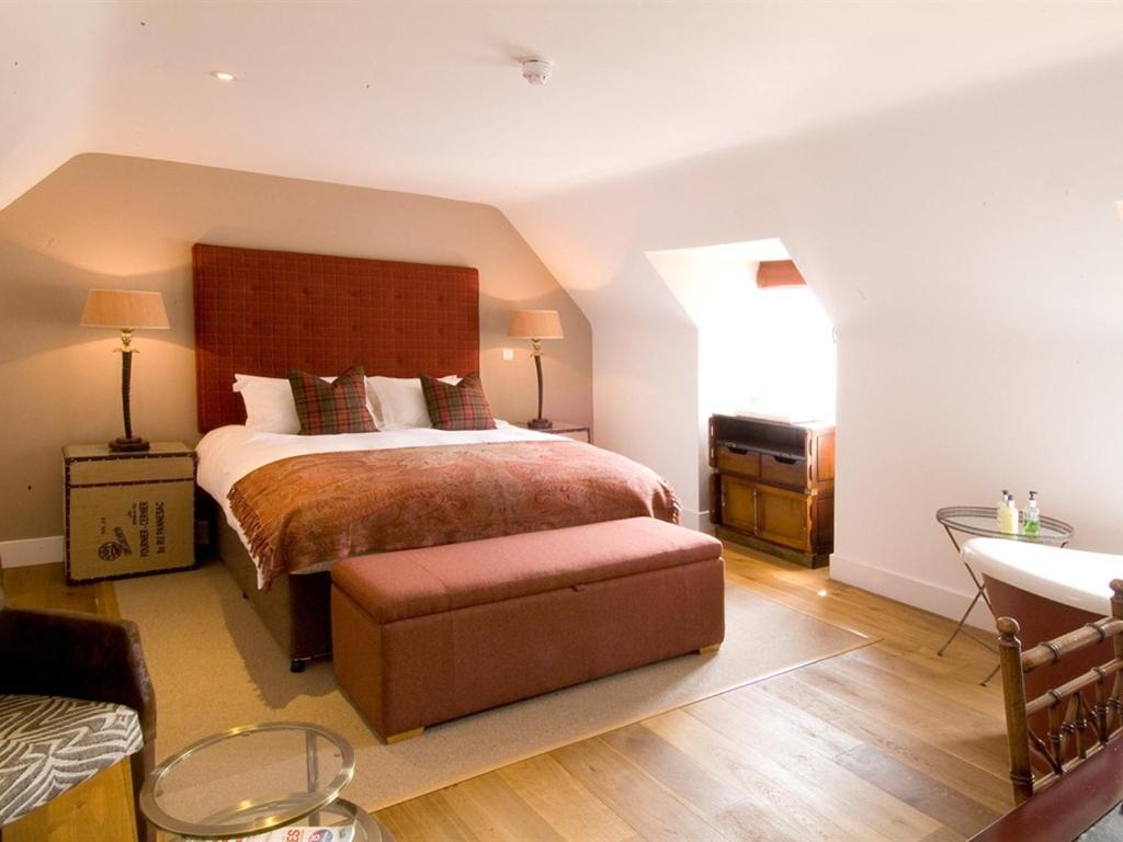 吉尔福德珀西阿姆斯酒店的一间卧室配有一张大床,里面设有长凳