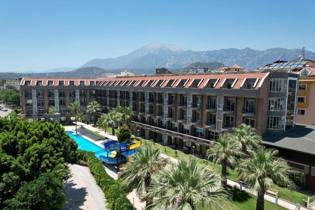 凯麦尔松树园海滩酒店的公寓大楼设有游泳池和棕榈树