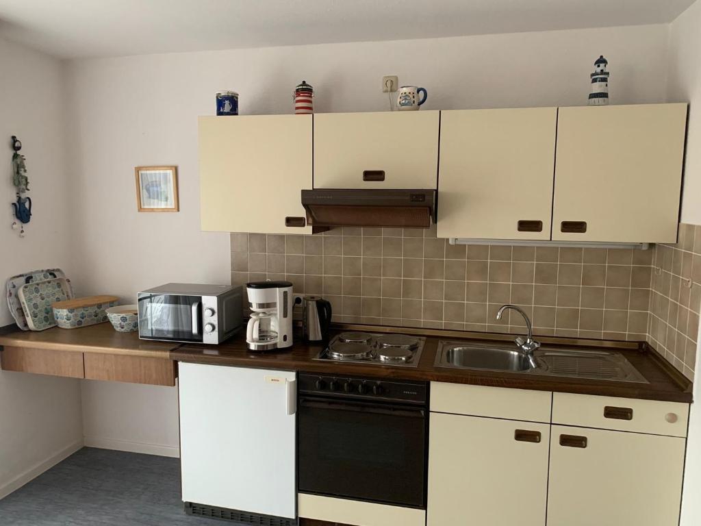 达默FeWo Seeschloss Nr 5的厨房配有白色橱柜和黑炉灶烤箱。