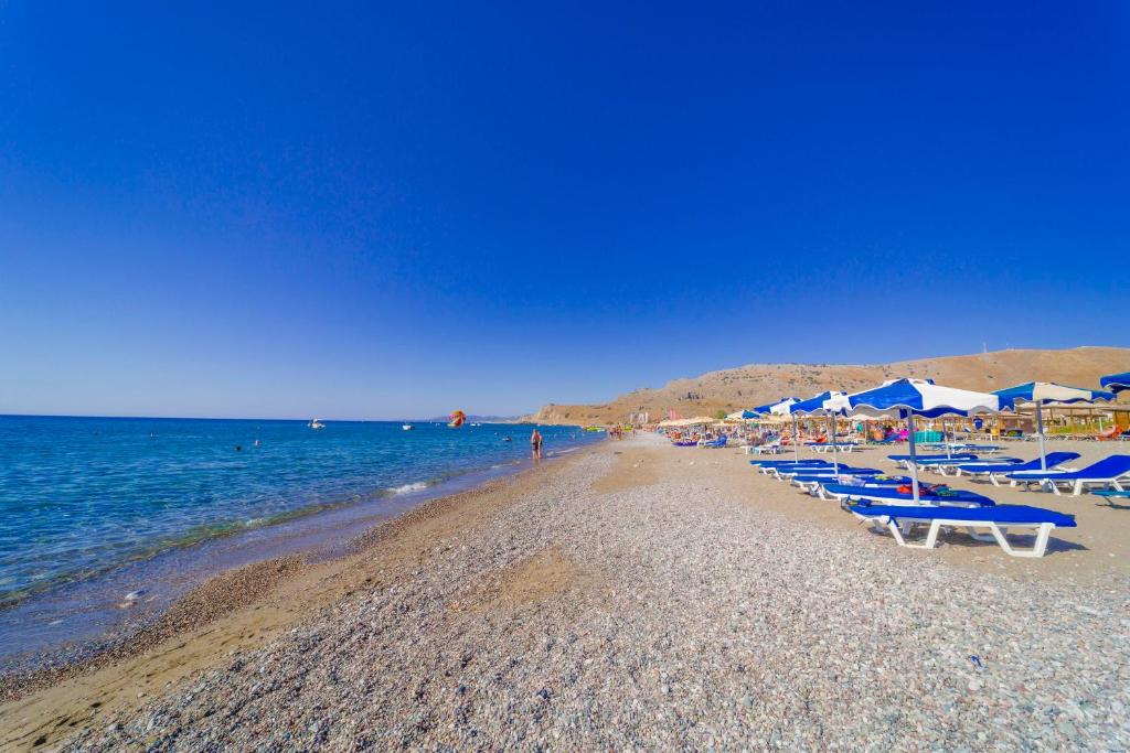 拉多斯Amaryllis front beach hotel的海滩上设有椅子和遮阳伞,还有大海