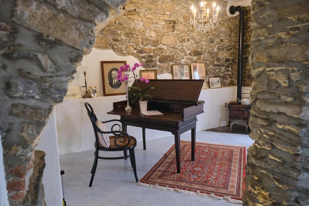 ArnascoAgriturismo Le Merline的钢琴,带椅子和桌子的房间